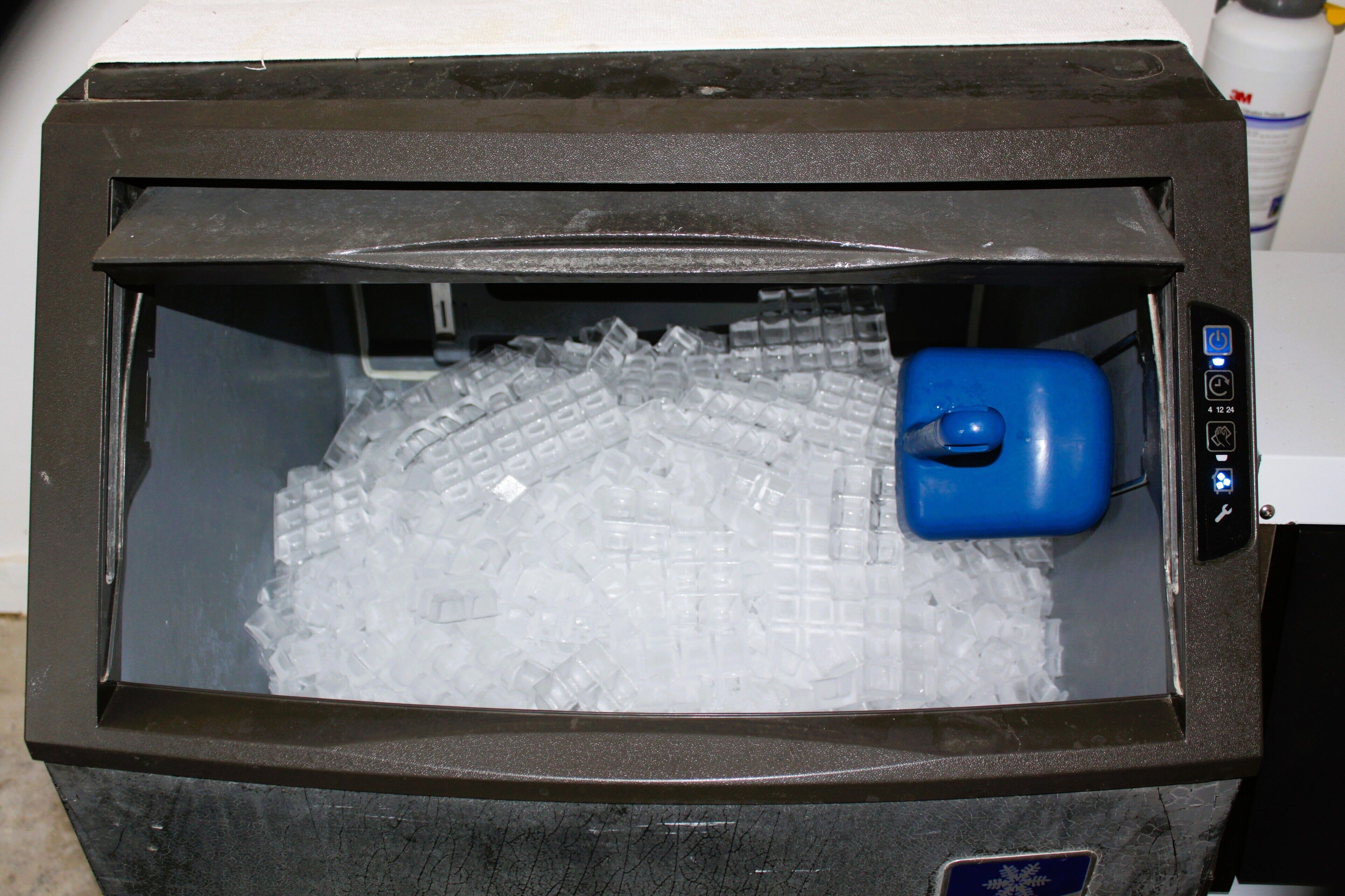Un refrigerador con dispensador de agua azul y compartimento para hielo.