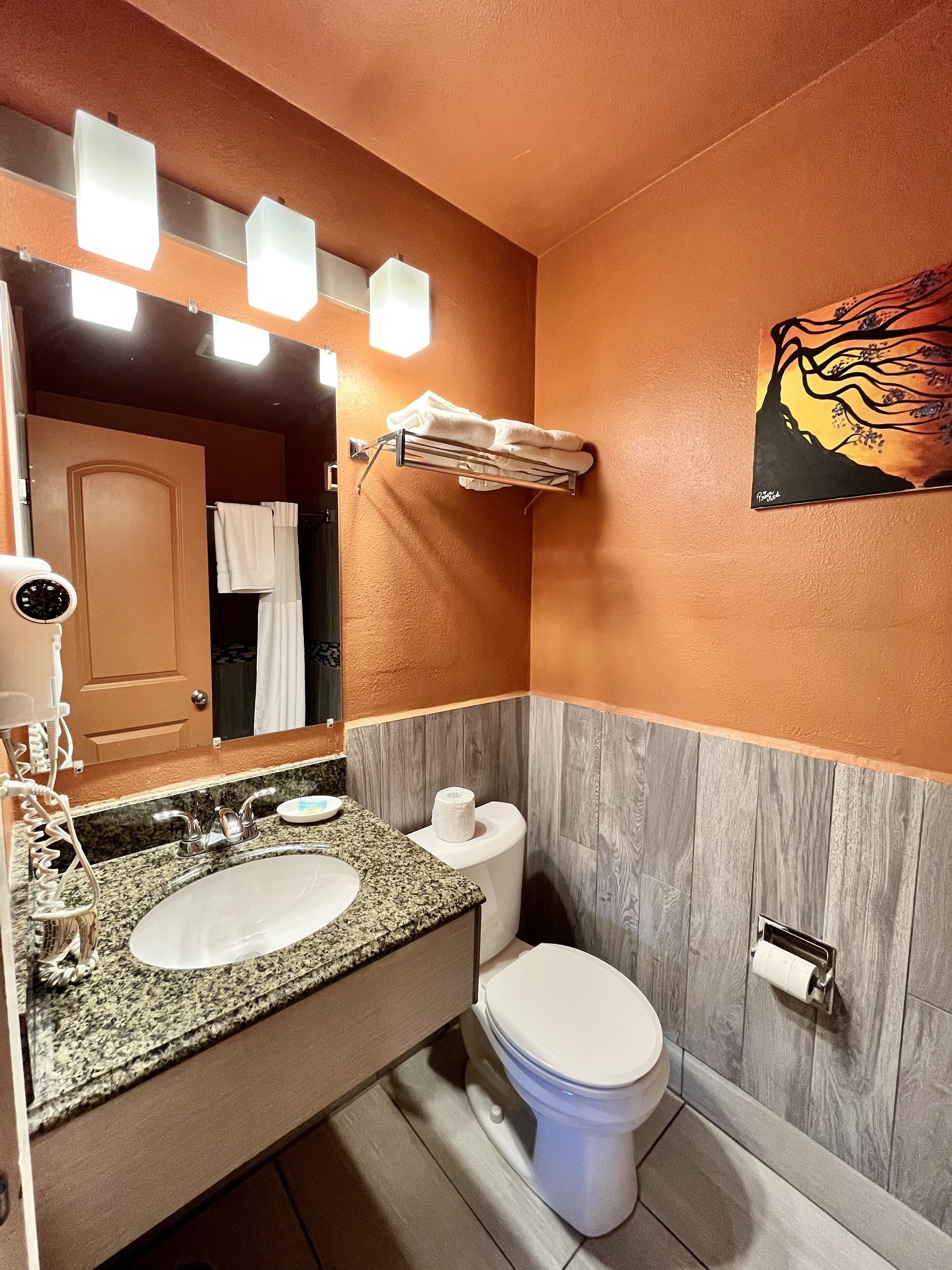 A bathroom with a granite countertop sink, a white toilet, and a towel rack.