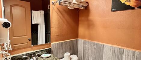 A bathroom with a granite countertop sink, a white toilet, and a towel rack.