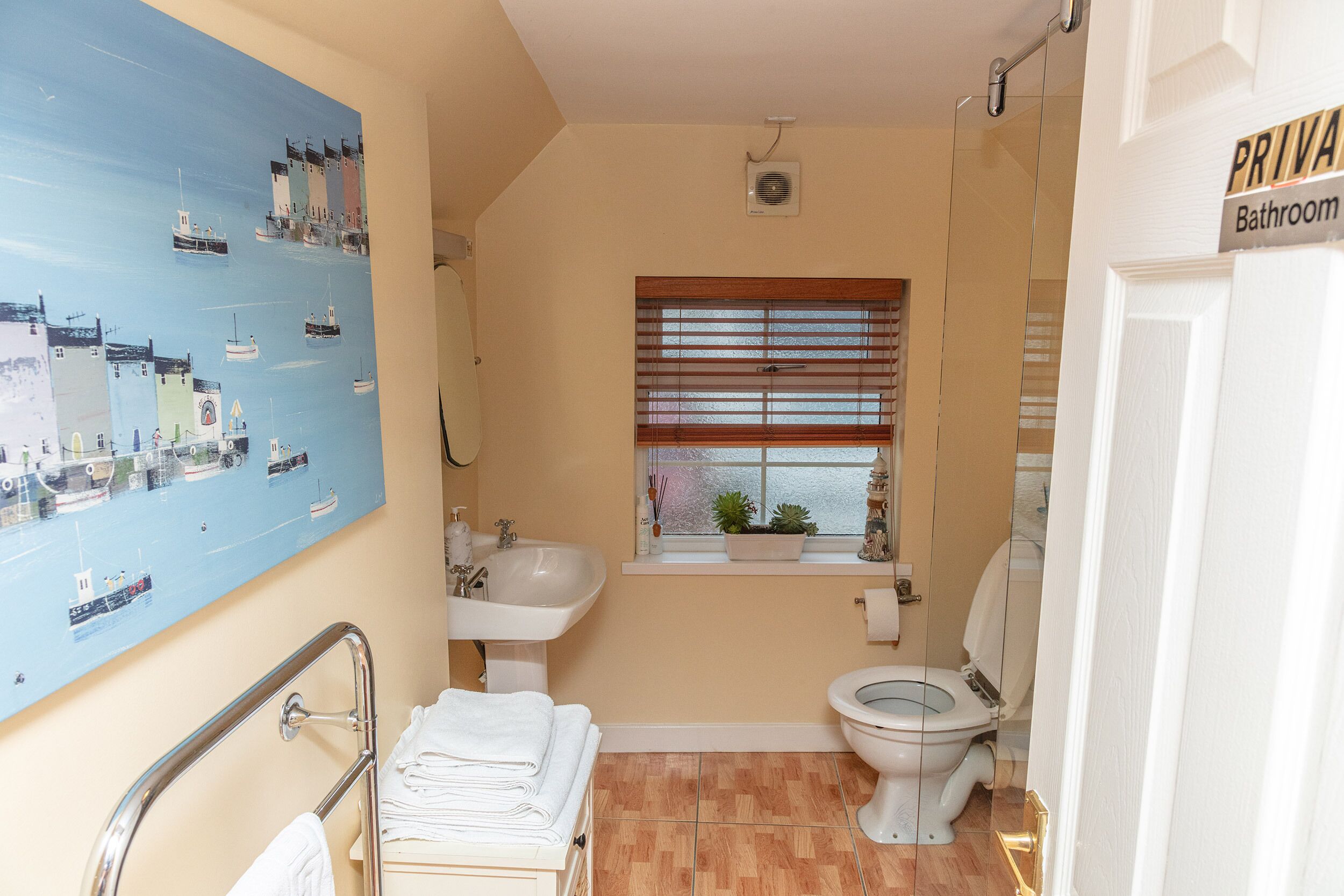 Een badkamer met toilet, wastafel en raam met zonwering.