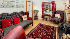 Una sala de estar acogedora con sofá, sillones, alfombra y chimenea.