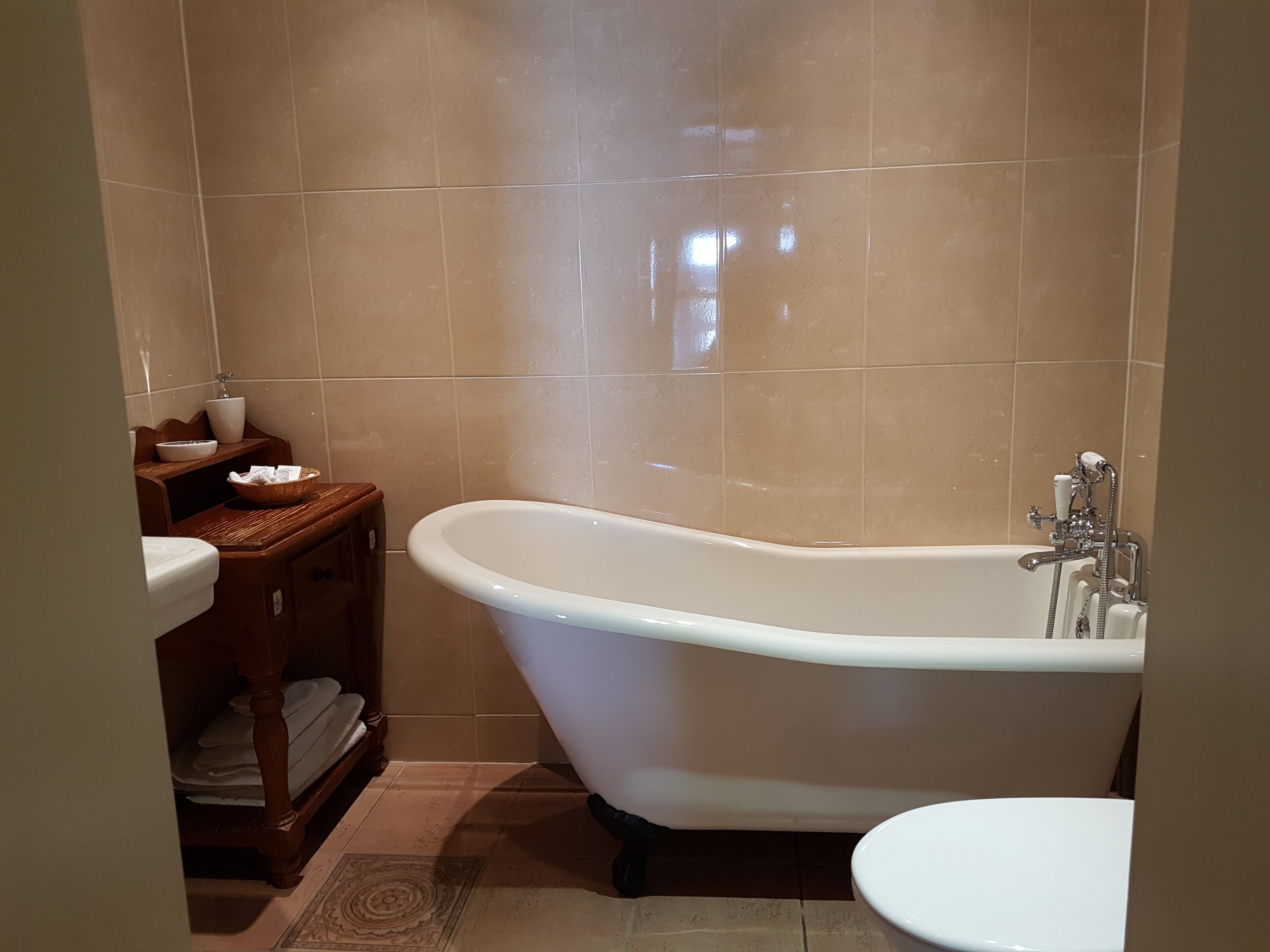 A bathroom with a freestanding bathtub, a toilet, and a wooden vanity with a sink.