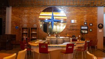 Un restaurant avec un mur en briques, un grand miroir rond et des chaises rouges.