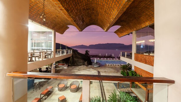 A rooftop terrace with seating and a view of the sea at dusk. - Portogalo Suite Hotel (Angra dos Reis)