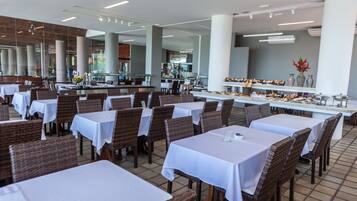 Un ristorante con diversi tavoli e sedie, un'area buffet e un grande pilastro.