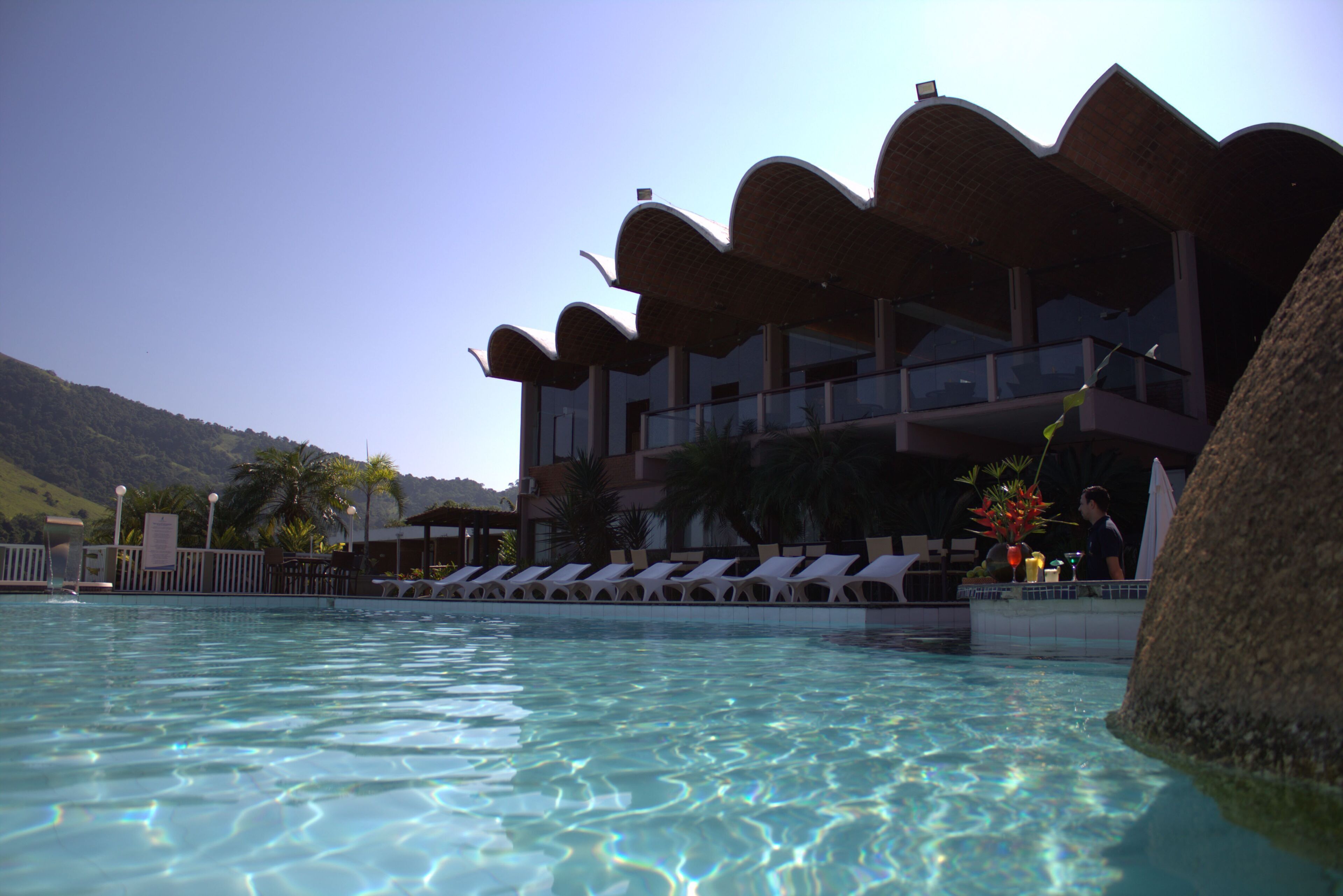 A pool area with lounge chairs and a building with a unique architectural design.