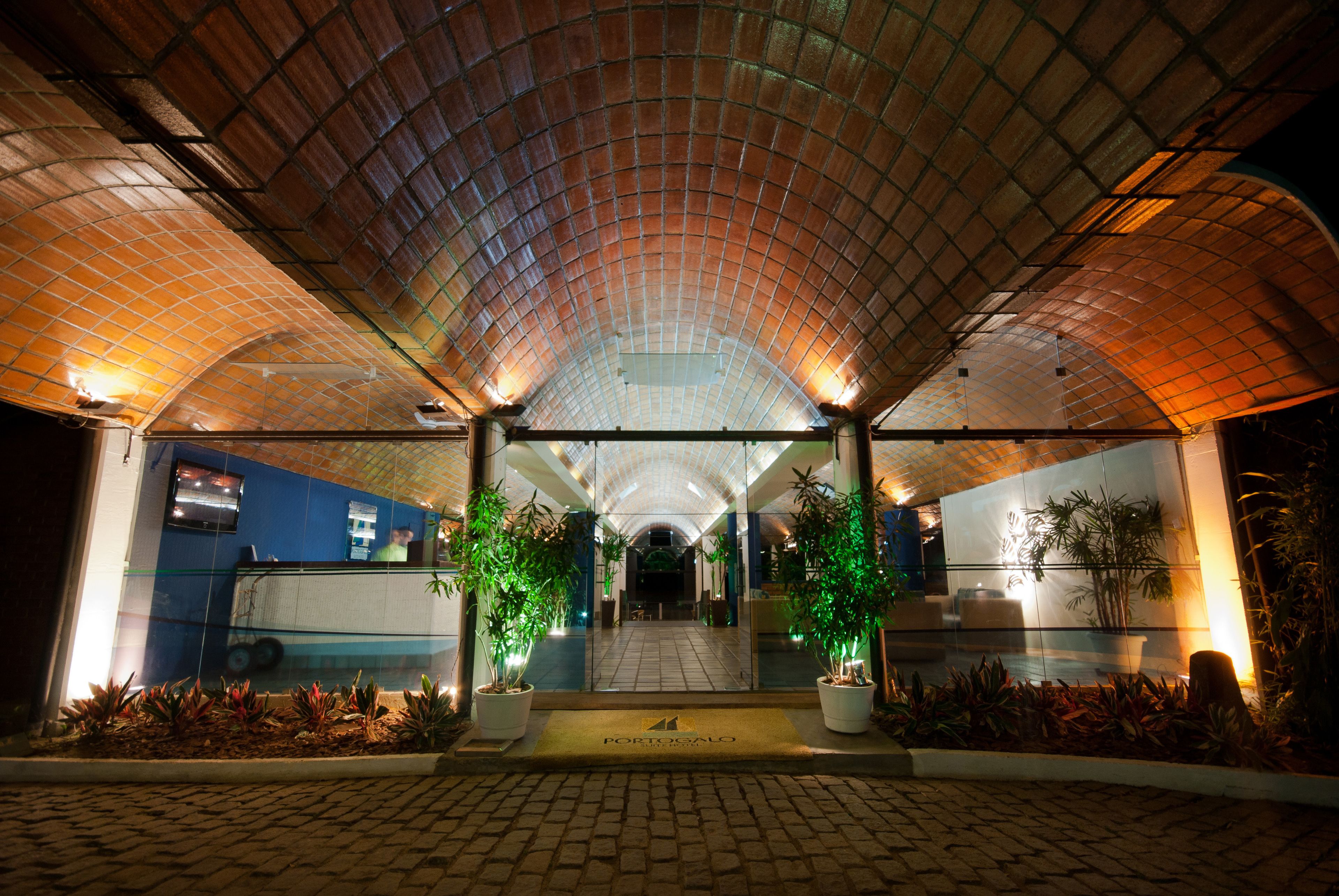 A covered entrance with a tiled roof, potted plants, and a welcome mat.