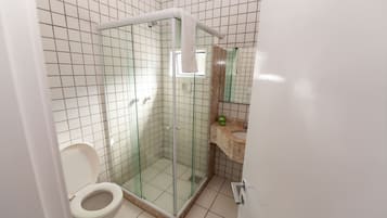A bathroom with a glass-enclosed shower, a toilet, and a sink with a mirror above it.