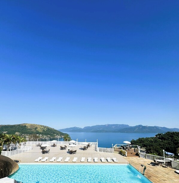 Zona junto a la piscina con sillones de descanso y vista al mar.