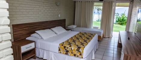 A hotel room with a brick wall, two beds, a wooden nightstand, a desk, and a view of the outdoors.
