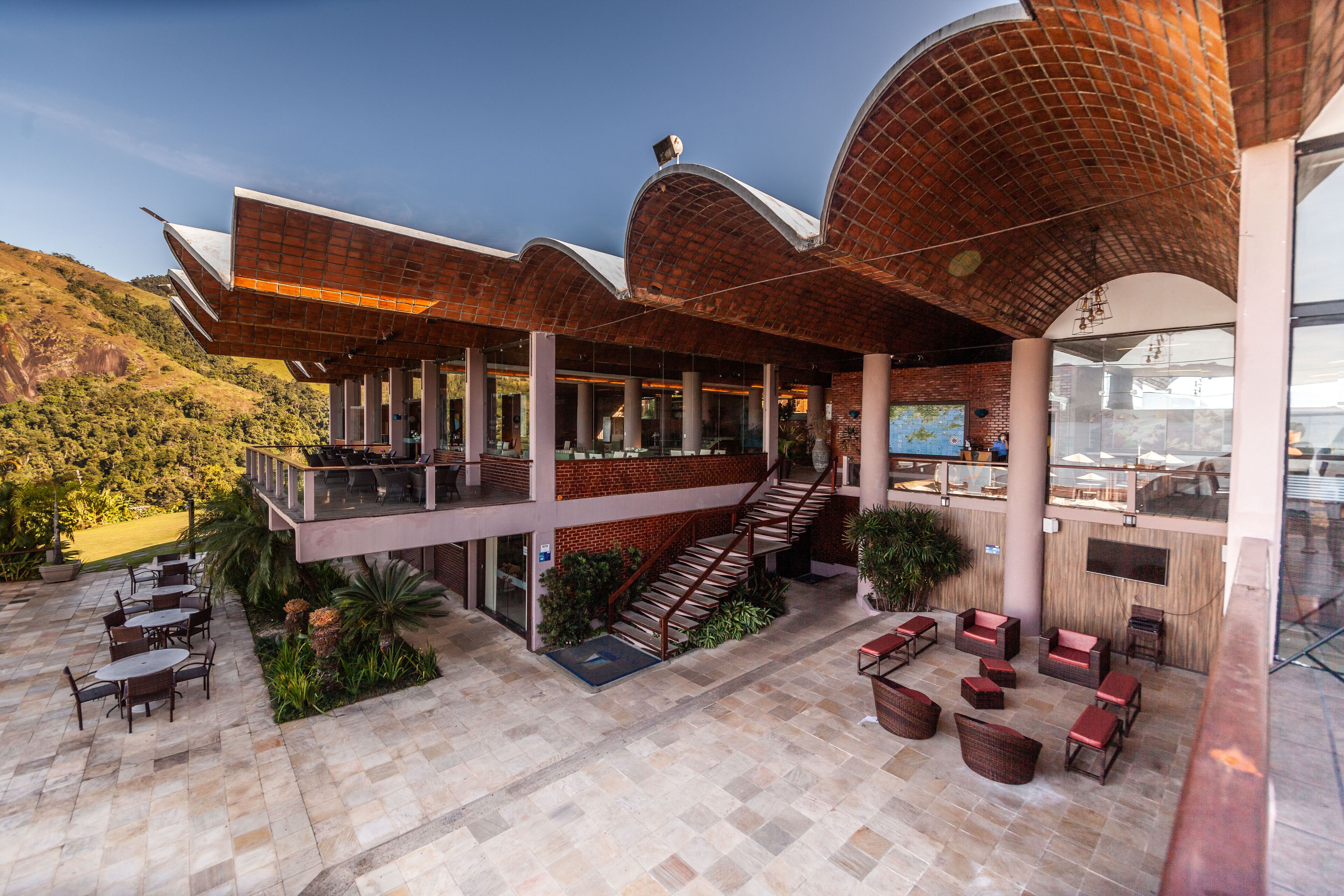 Un edificio moderno con terraza, asientos exteriores y una escalera que lleva a un nivel superior.