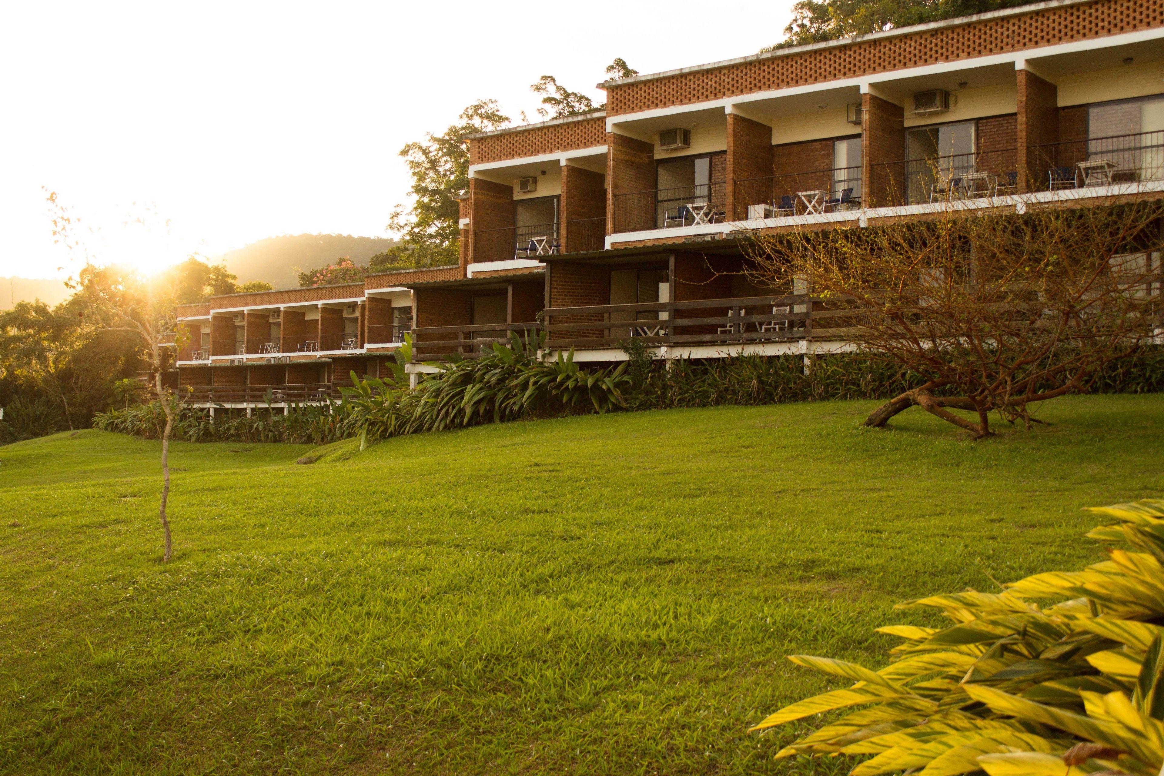 A multi-story building with a brick facade, balconies with outdoor furniture, and a well-maintained lawn.