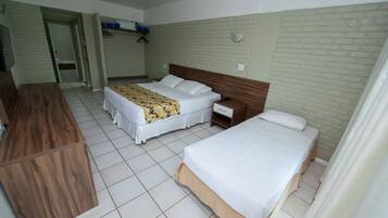 A hotel room with two beds, a wooden desk, a wardrobe, and a bathroom visible through an open door.