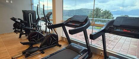Une salle de sport équipée de tapis de course, de vélos d’appartement et d’un appareil d’aviron.