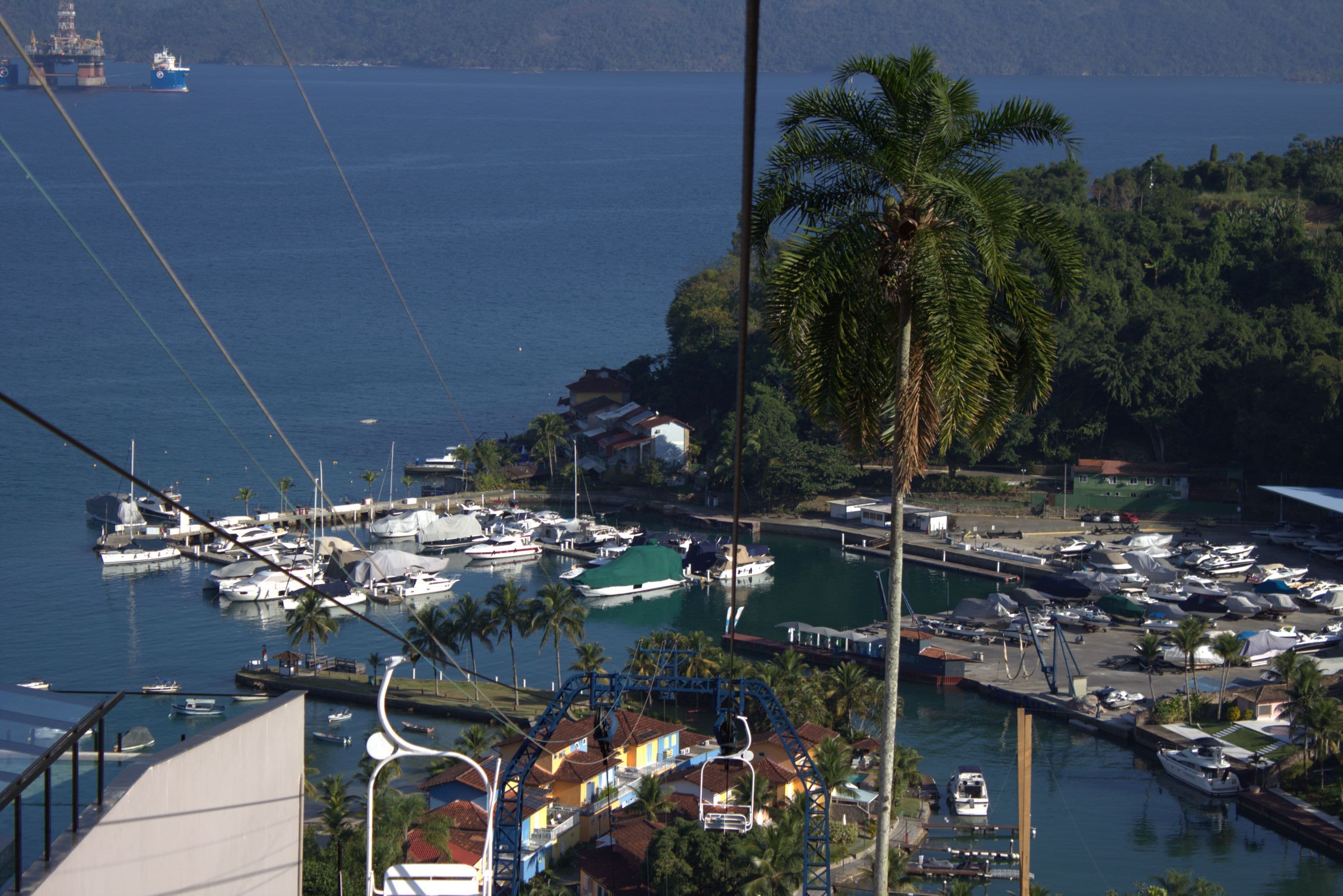 Un puerto deportivo con barcos amarrados, una montaña rusa y vista al mar.