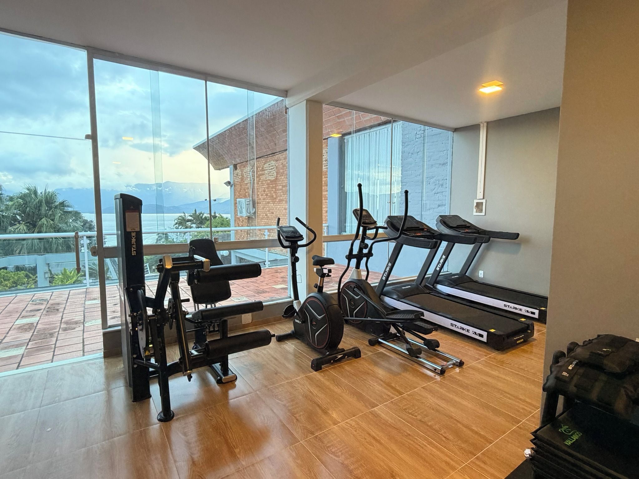 A gym with exercise equipment, large windows, and a view of mountains.