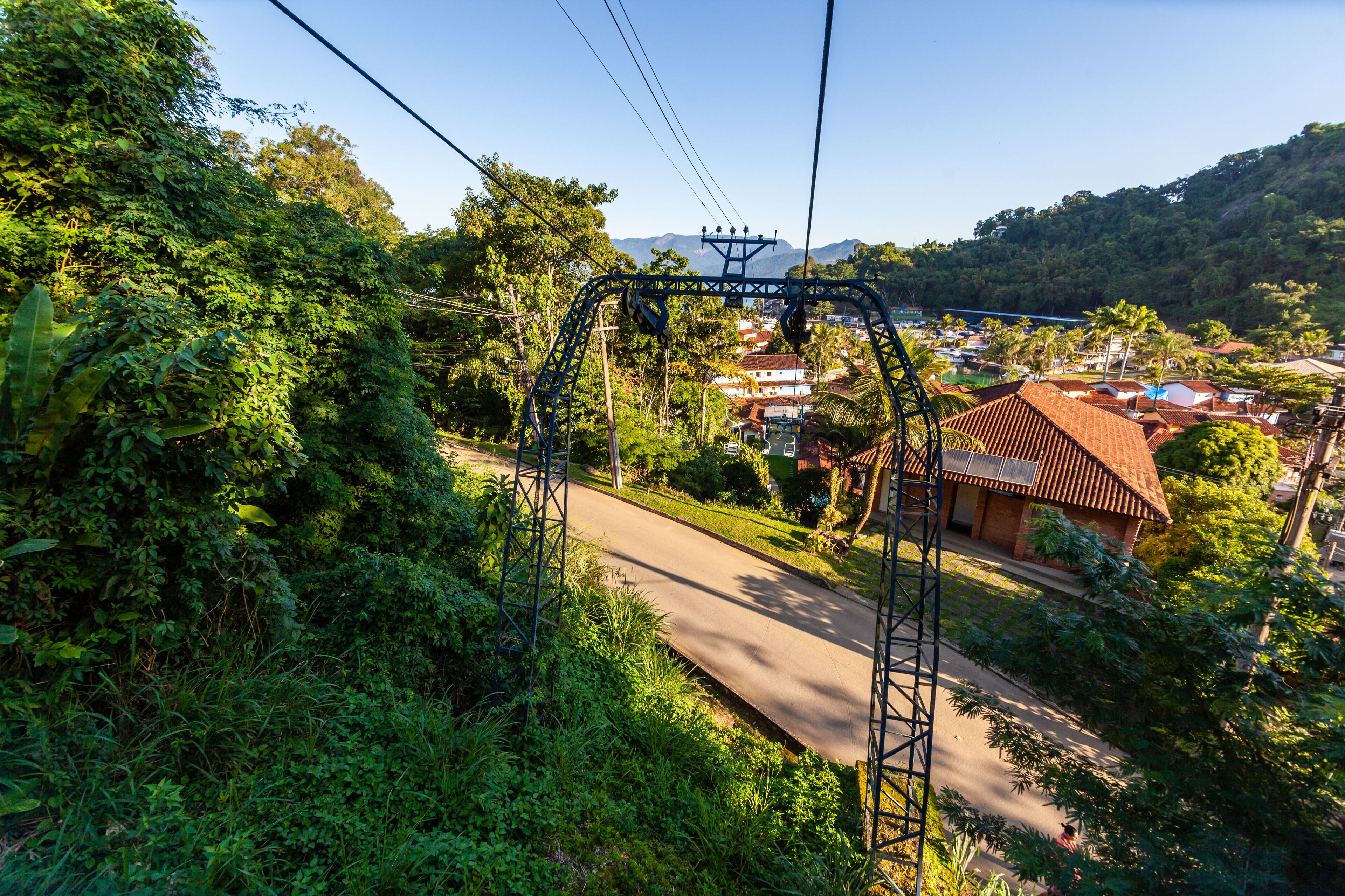Un sistema de teleférico con una vista despejada de una carretera y edificios al fondo.