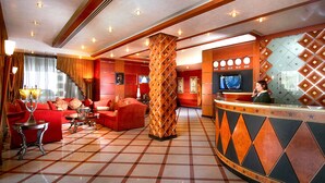 A hotel lobby with a check-in counter, seating area with sofas, and a large pillar. - Elite Tower (Manama)