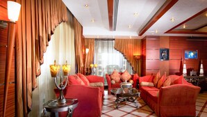 A spacious living area with red sofas, a coffee table, and a fireplace. - Elite Tower (Manama)
