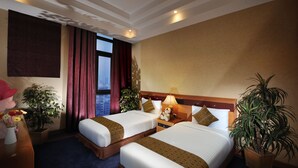 A hotel room with two beds, a large window, a view of the city, and several potted plants. - Elite Tower (Manama)