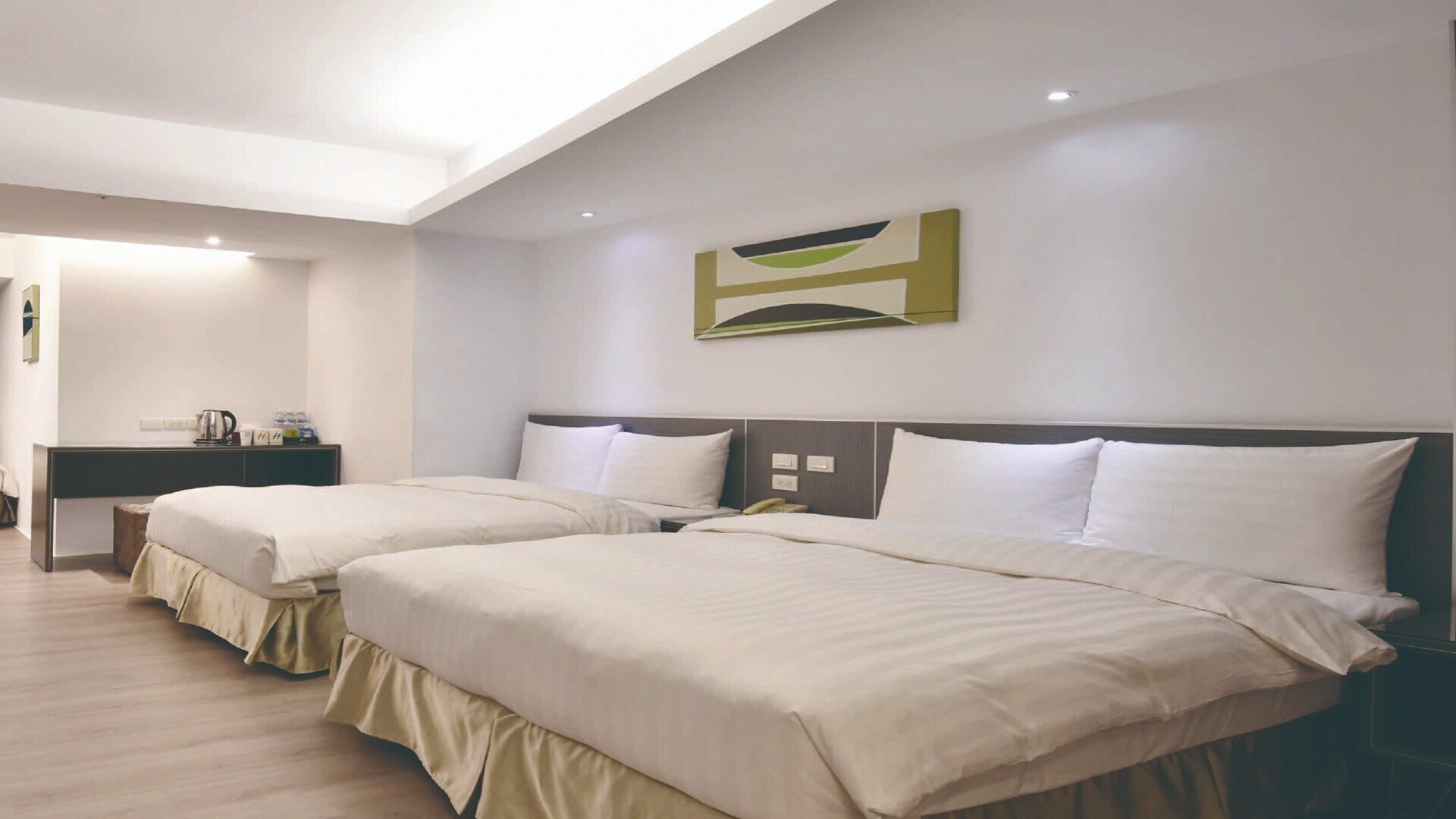 Habitación de hotel con dos camas, un escritorio y una obra de arte moderna en la pared.
