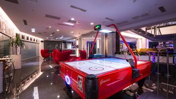 Una mesa de hockey sobre hielo roja en un vestíbulo moderno con sillas rojas y una planta en maceta.