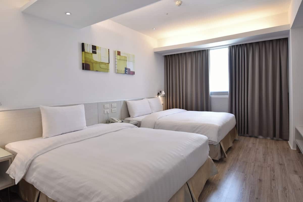 Habitación de hotel con dos camas, un ventanal con cortinas y un cuadro abstracto en la pared.
