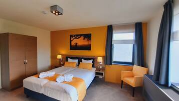 A hotel room with a large bed, two bedside tables with lamps, a chair, a wardrobe, and a painting on the wall.