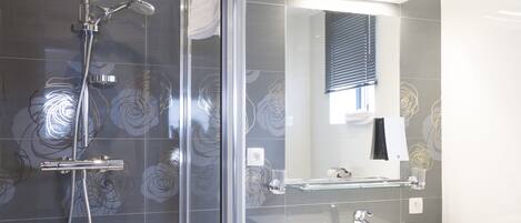 A modern bathroom with a glass-enclosed shower, a white vanity, and a large mirror.