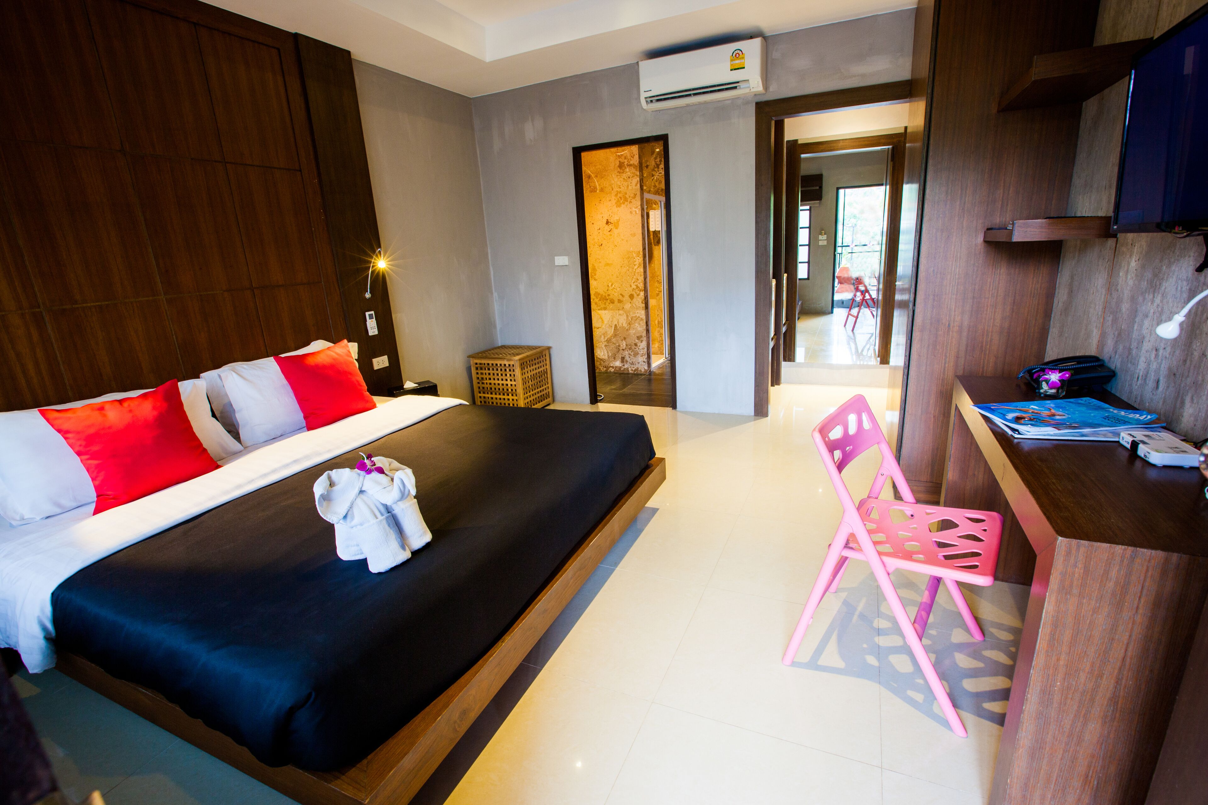 A hotel room with a large bed, a desk with a chair, and a door leading to a balcony.