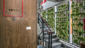 A staircase with a wooden door labeled "AP202" and a wall with vertical garden panels. - Amenity Apartel Samui (Koh Samui)