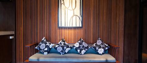 A wooden panel wall with a framed artwork above a bench with floral cushions.