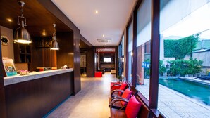 A reception area with a counter, seating, and a view of a swimming pool. - Amenity Apartel Samui (Koh Samui)