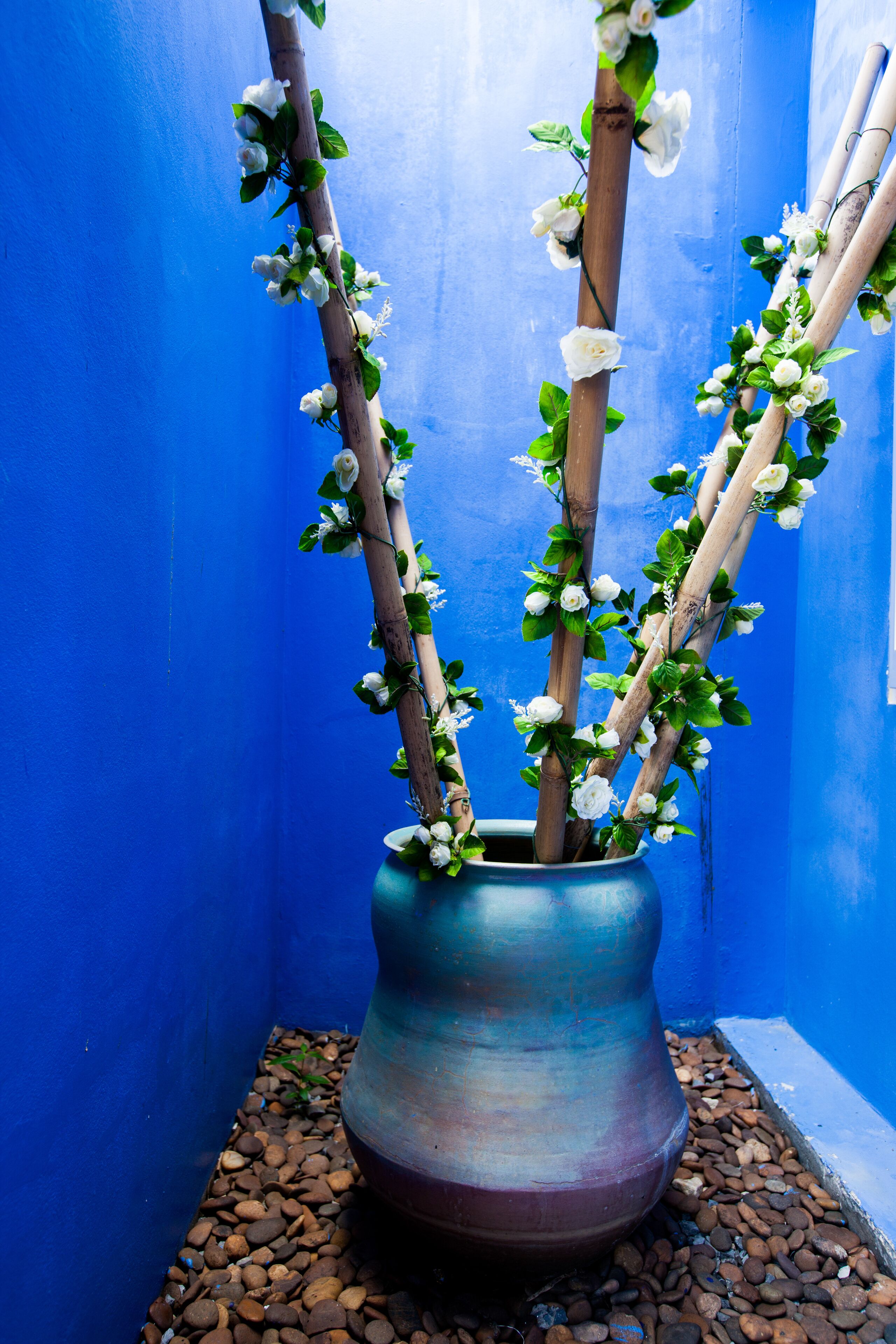 Un mur bleu avec un vase contenant des branches ornées de fleurs blanches.