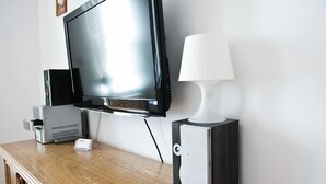 En tv som är monterad på väggen, en vit lampa och ett litet skåp med en logotyp.