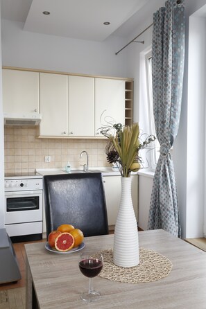A modern kitchen with white cabinets, a sink, and a window with patterned curtains.