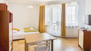 Ett rum med en säng, ett bord, en stol, ett skrivbord, en tv och ett fönster med gardiner.