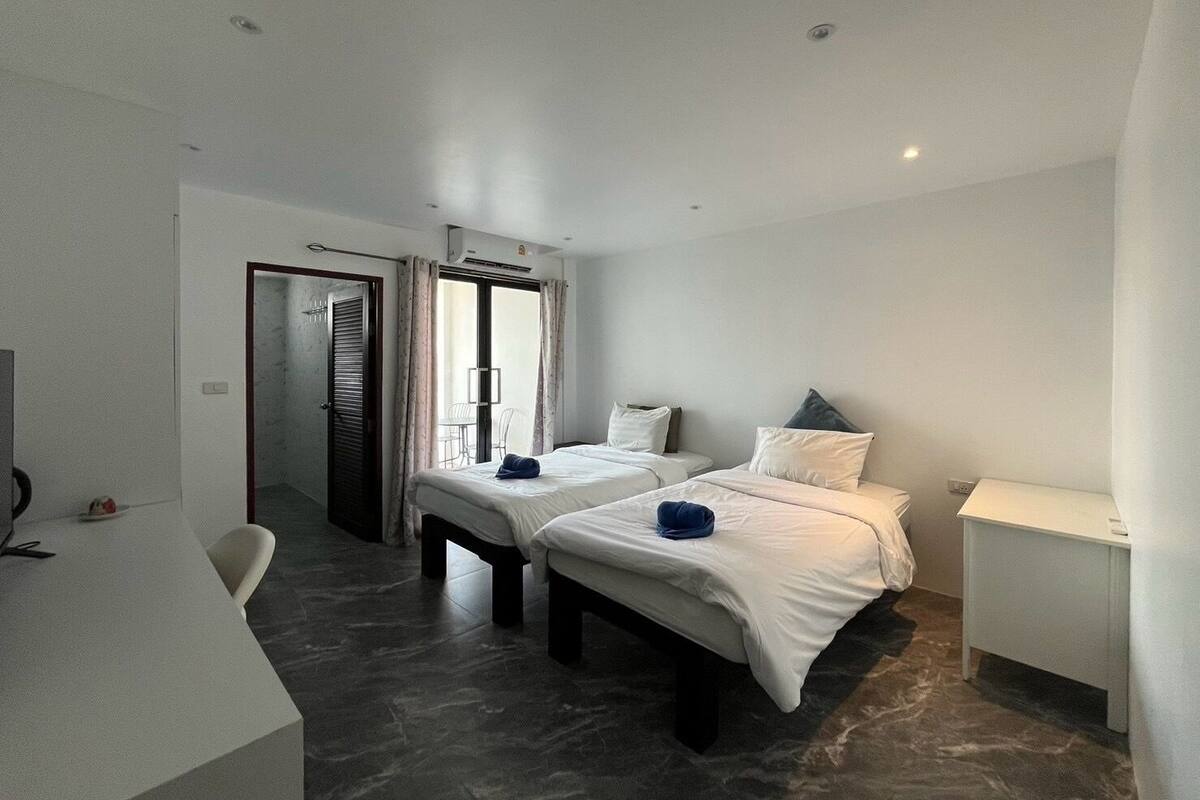 A hotel room with two beds, a desk, and a chair.