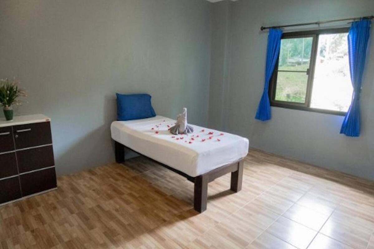 A room with a bed, a dresser, and a window with curtains.