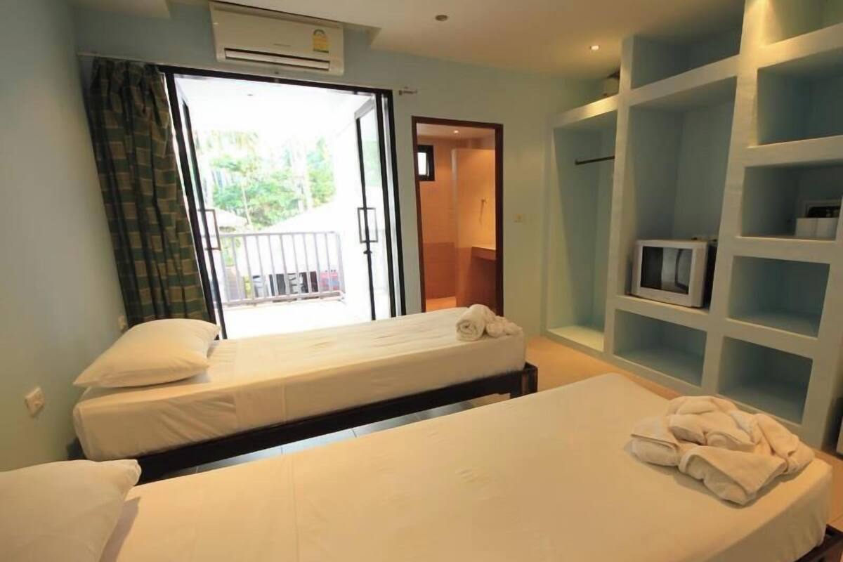 A hotel room with two beds, a balcony, a TV, and a wardrobe.