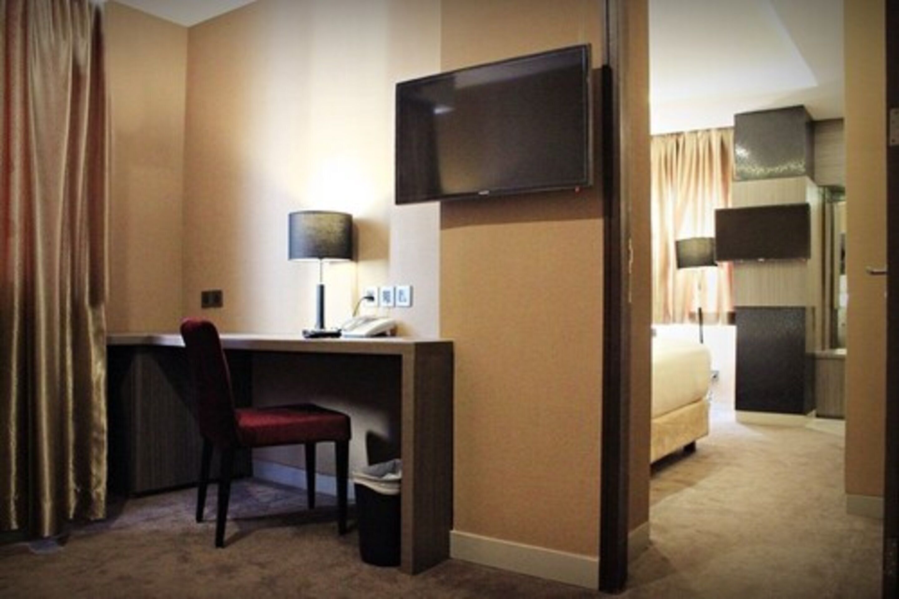 Habitación de hotel con escritorio, silla, televisor y cama.