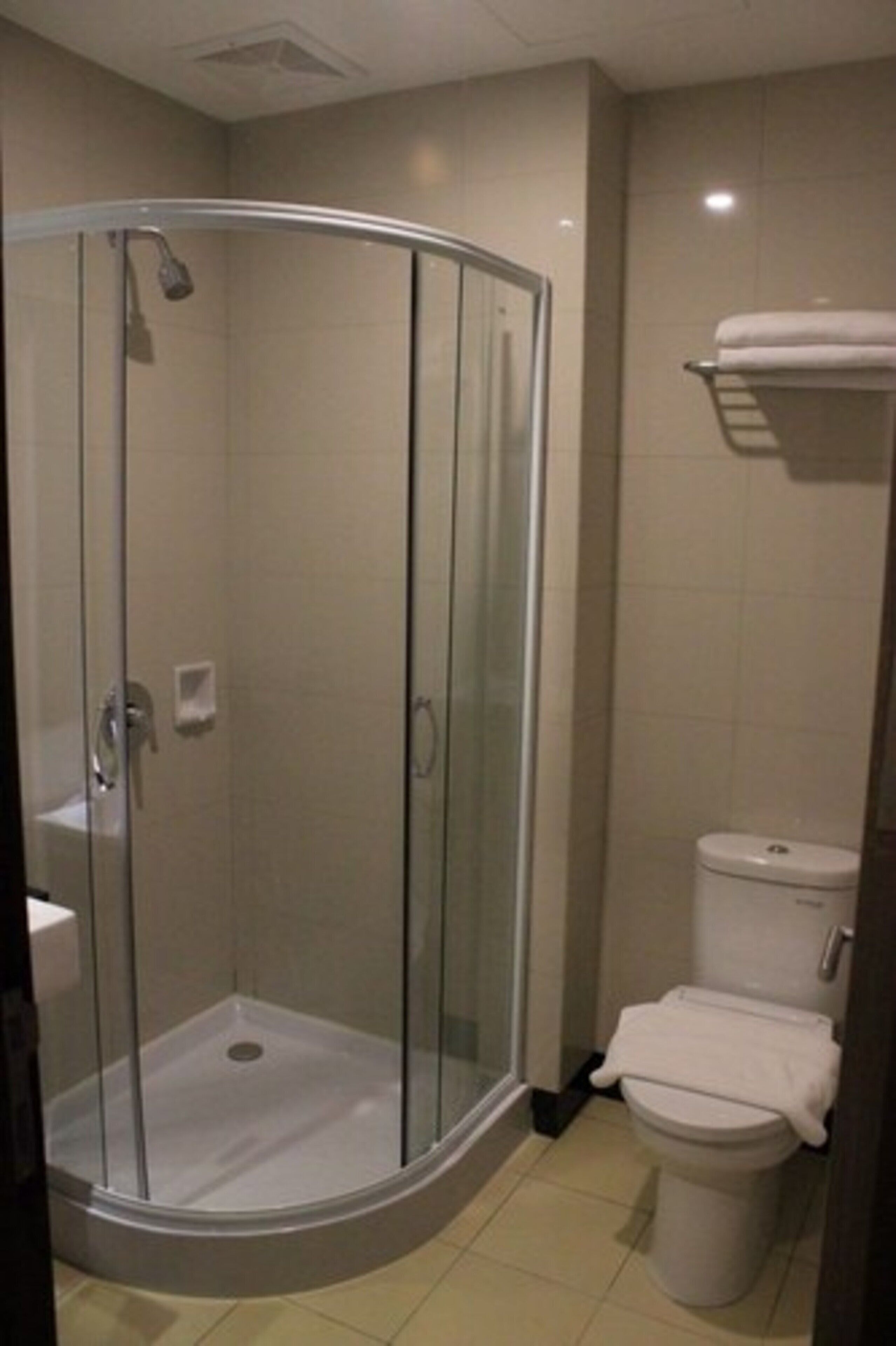 Un baño moderno con ducha acristalada, inodoro y lavamanos.