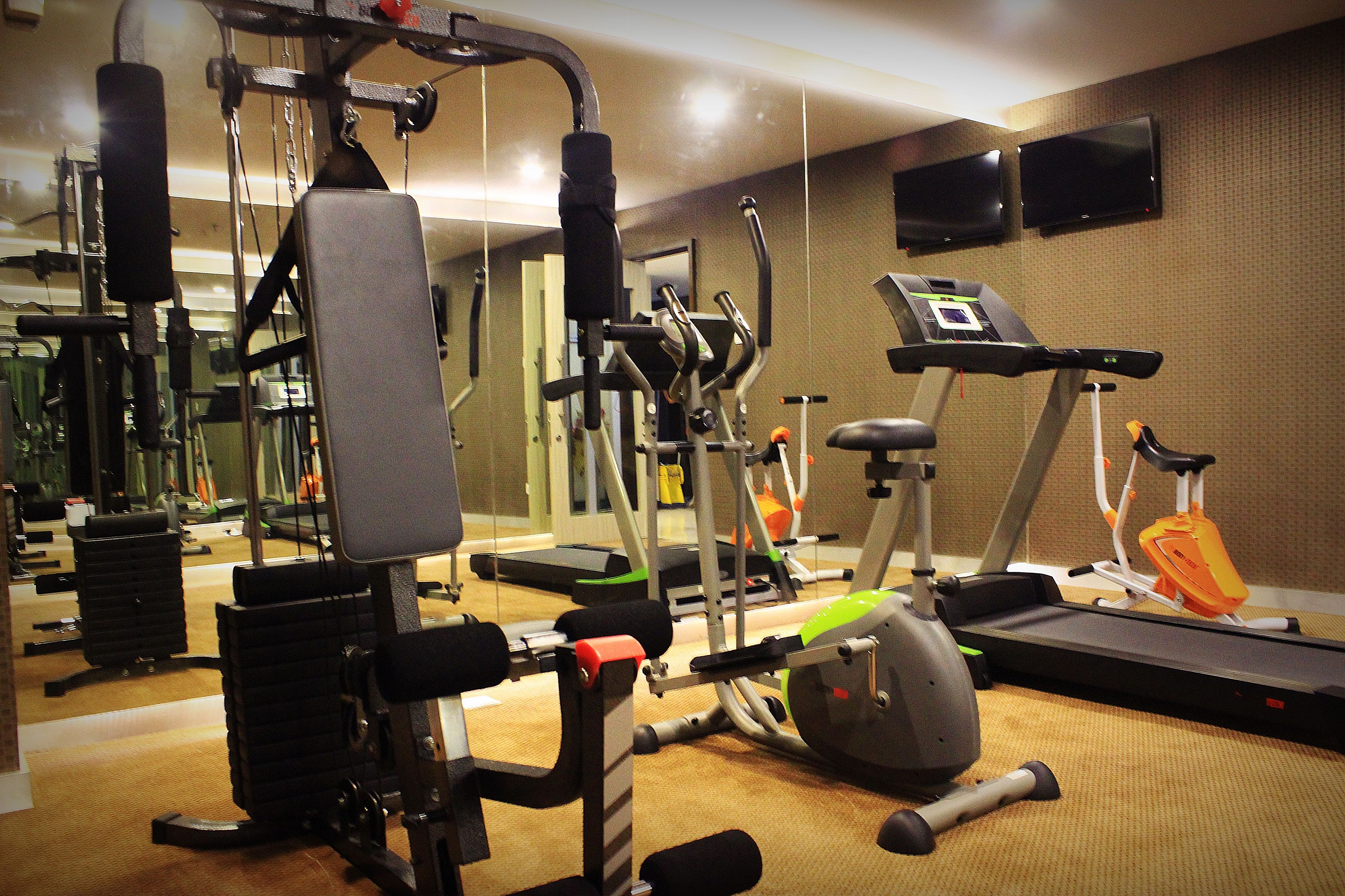 A gym with various exercise equipment, including a treadmill, elliptical, and weight machines.
