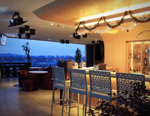 A bar area with a city view, bar stools, and a Christmas garland. - Biz Hotel Batam (Batam)