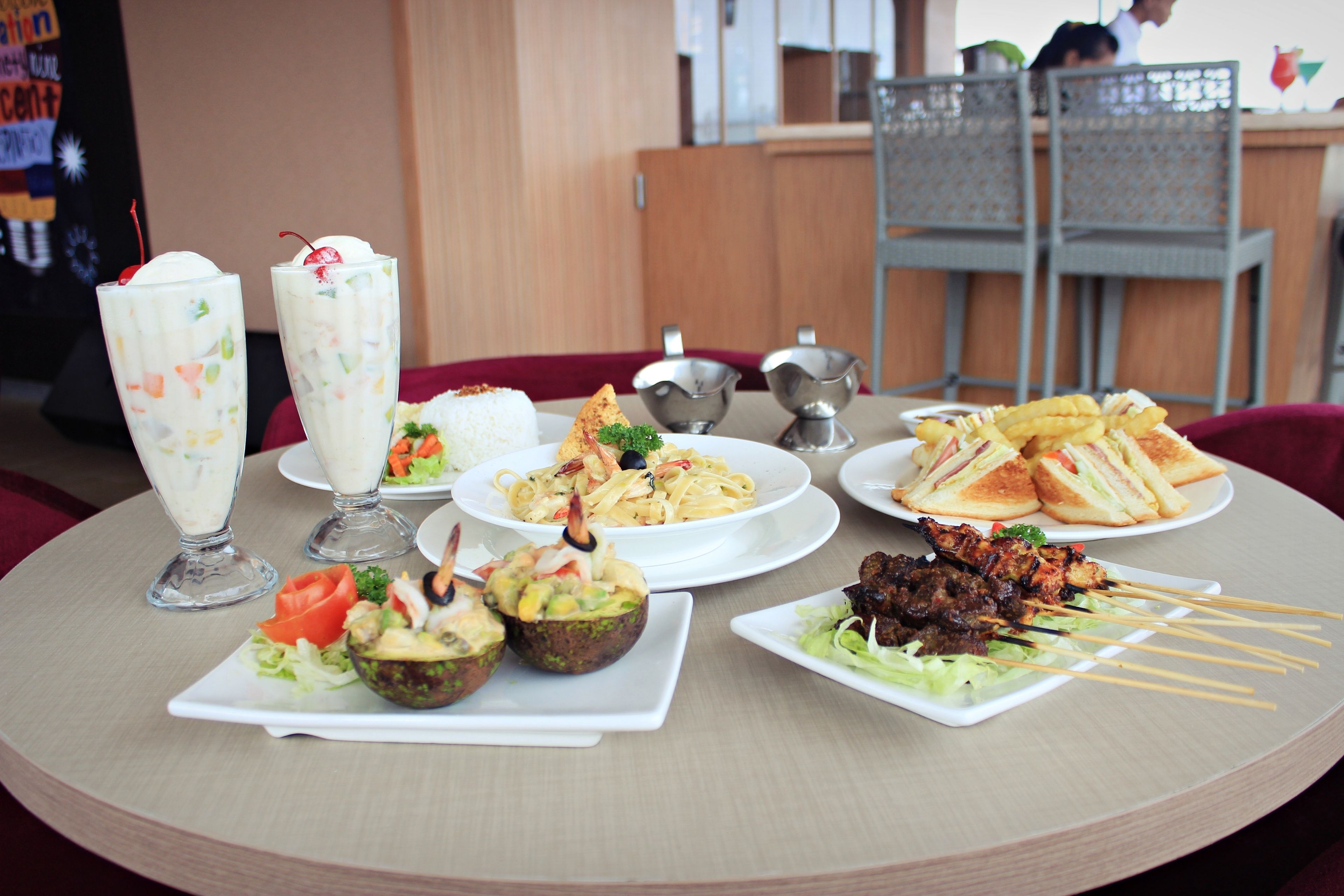 Una mesa con varios platos, incluyendo pasta, sándwiches y brochetas.