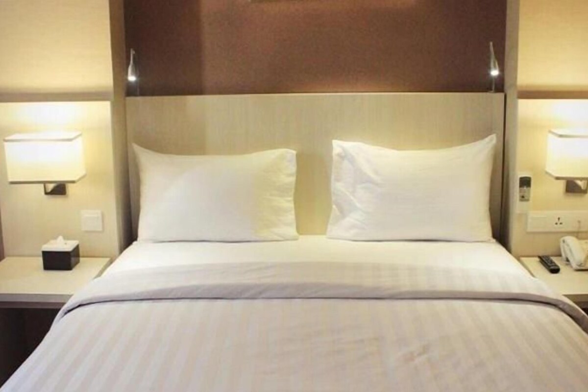 A hotel room with a bed, two bedside lamps, a nightstand, and a telephone.
