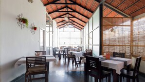 A spacious dining area with high ceilings and large windows, featuring multiple tables and chairs. - Maple Suites Serviced Apartments (Bengaluru)