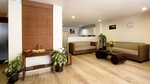 A living room with a sofa, a coffee table, and potted plants. - Maple Suites Serviced Apartments (Bengaluru)