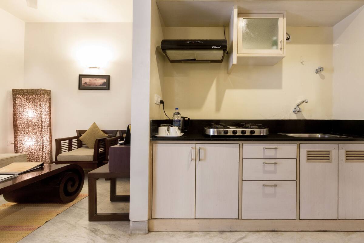 A compact kitchen with white cabinets, a black countertop, and a built-in microwave.