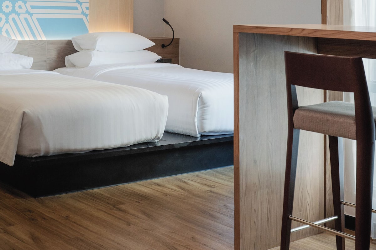 A hotel room with a bed, a desk, and a chair.